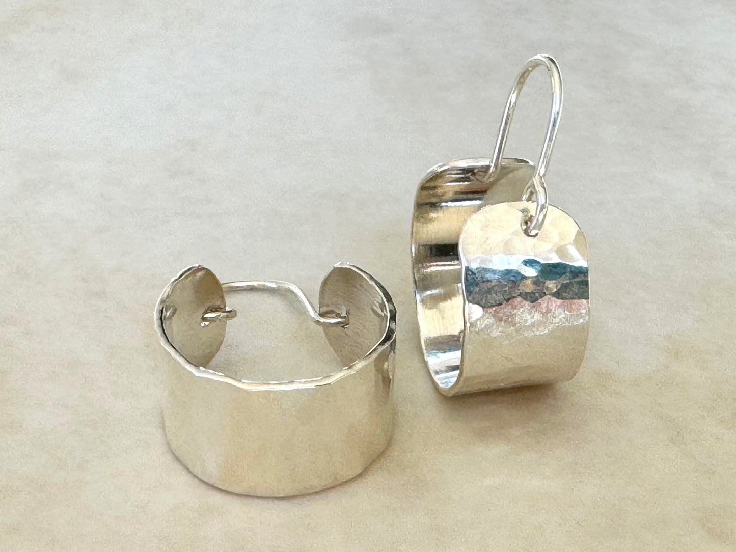 Pair of silver hoop earrings on a light beige background