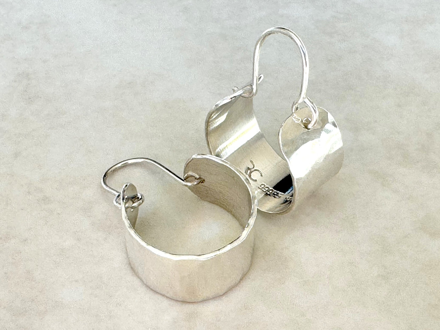 Pair of silver hoop earrings on a beige background
