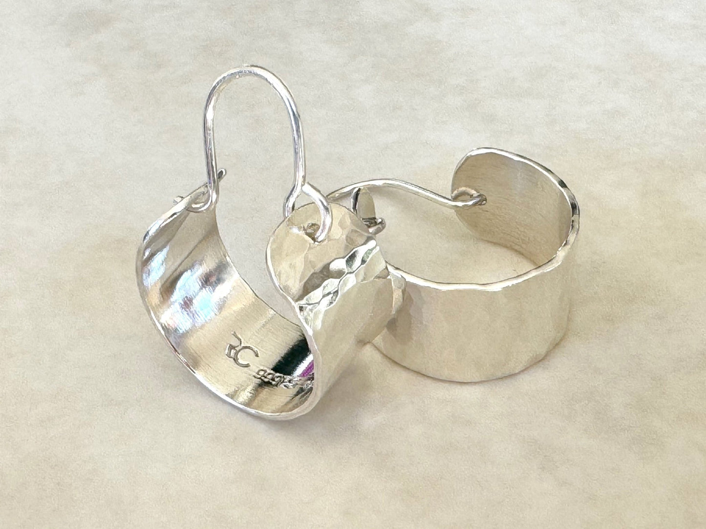 Pair of silver hoop earrings on a beige background