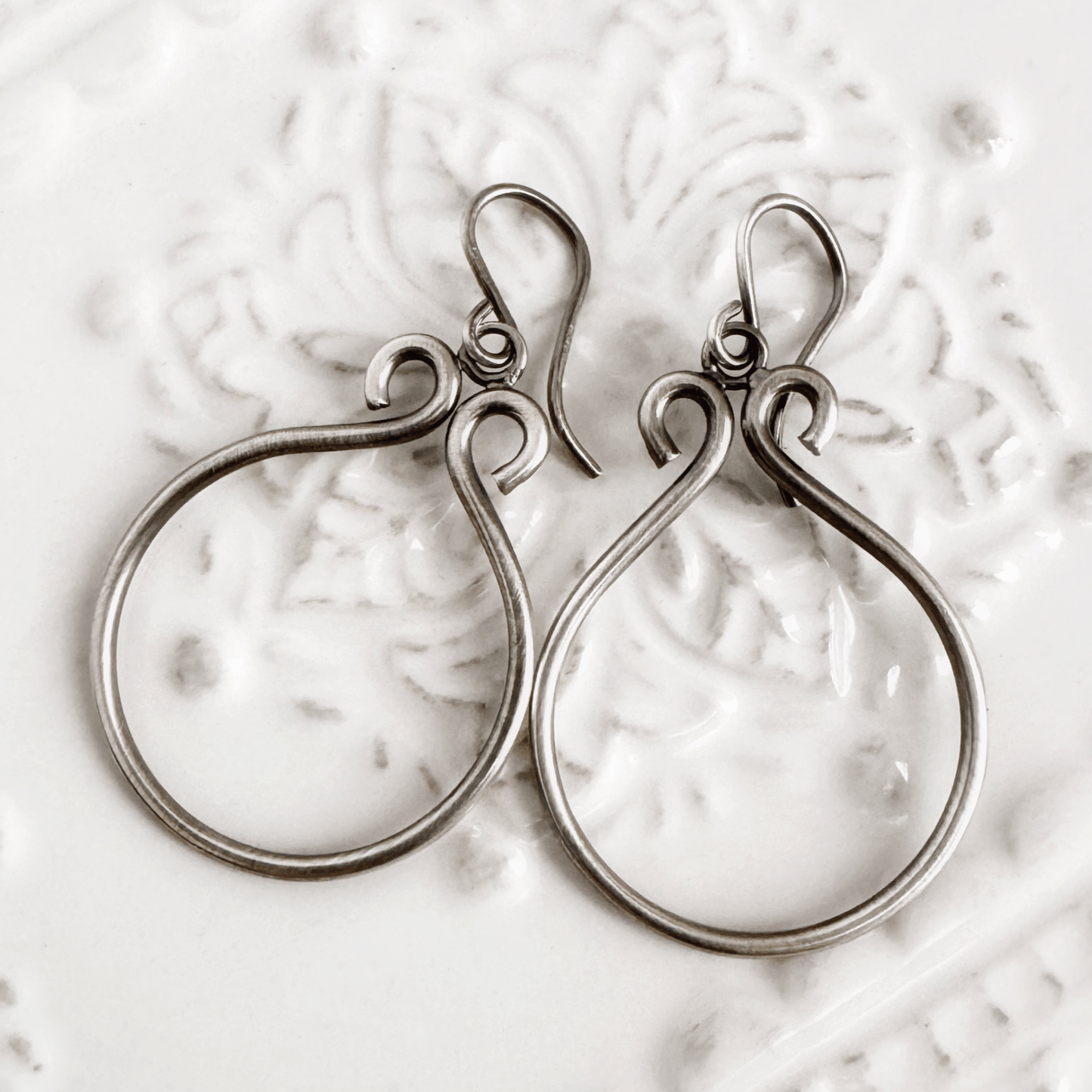 A set of sterling silver hoop earrings on a white background. The hoops have been oxidised.