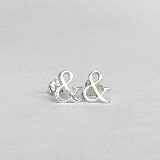 Sterling silver stud earrings shaped like ampersands on a light grey background