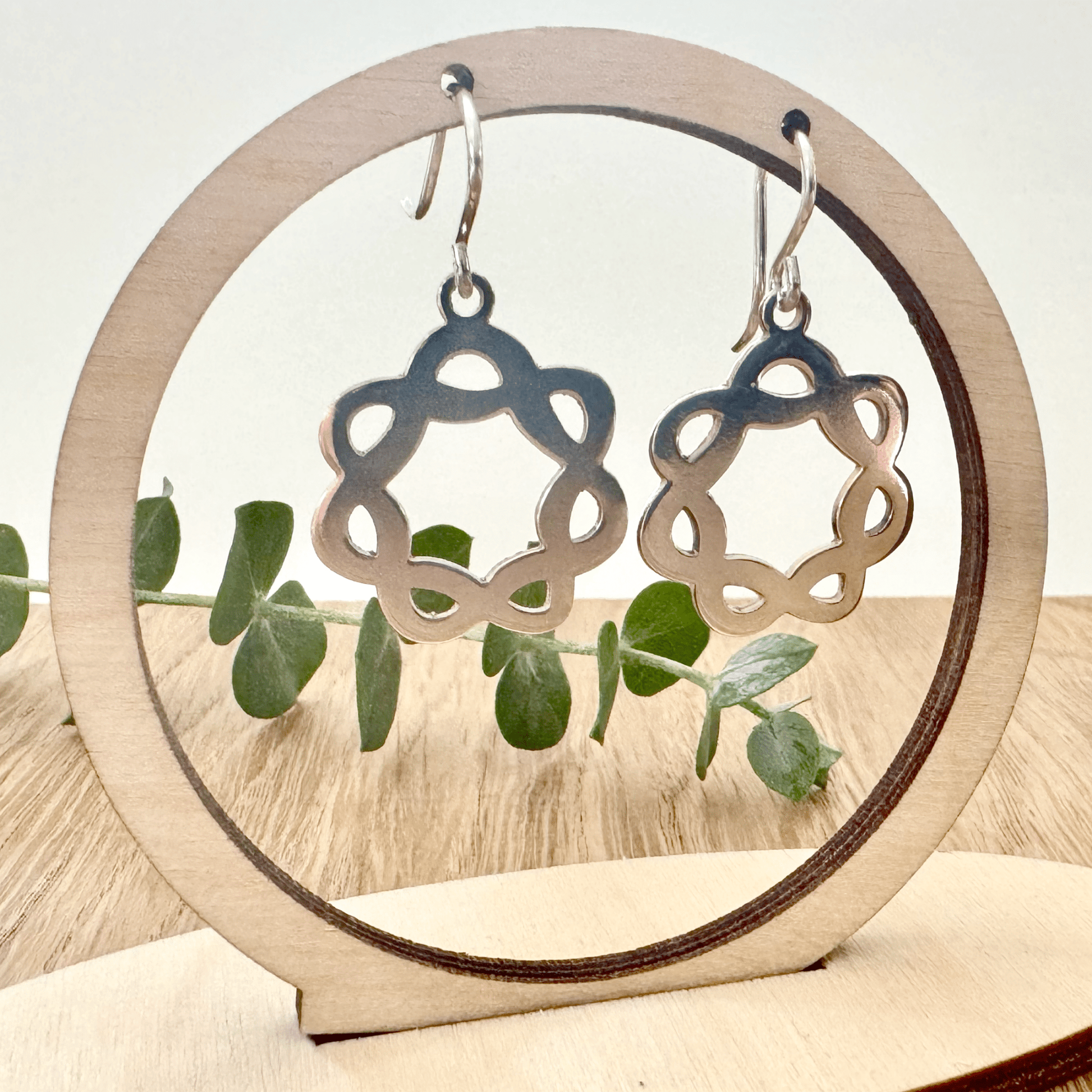 Silver earrings on a wooden stand with a natural background