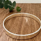Hammered sterling silver bangle on a wooden surface with a small sprig of eucalyptus leaves