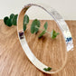 Hammered sterling silver bangle on a wooden surface with a small sprig of eucalyptus leaves