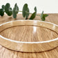 Hammered sterling silver bangle on a wooden surface with a small sprig of eucalyptus leaves