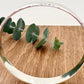 Hammered sterling silver bangle on a wooden surface with a small sprig of eucalyptus leaves