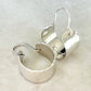 Pair of silver hoop earrings on a beige background