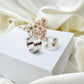 Silver hoop earrings with dried flowers on a white surface with beige fabric background
