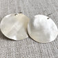 Pair of silver round earrings on a textured gray background