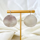 Pair of large hammered sterling silver disc earrings on a brass stand with a white fabric background