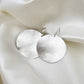 Silver earrings on a soft white fabric background