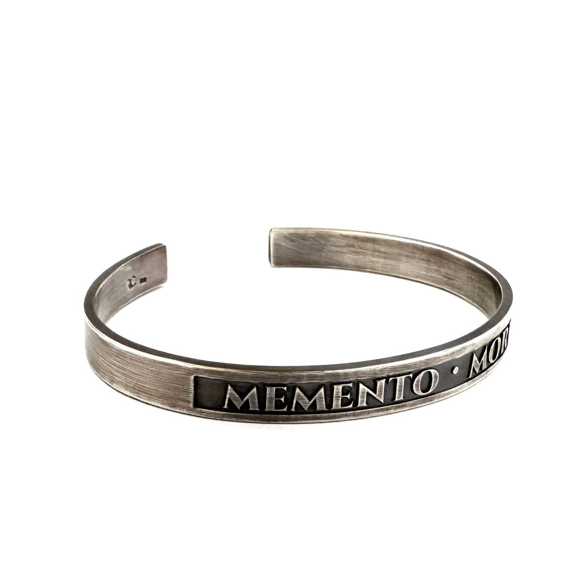 Close-up of MEMENTO MORI Roman lettering recessed into the silver cuff panel