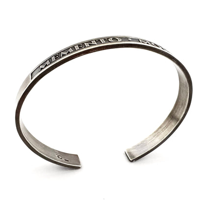 Angled view of the stoic memento mori cuff bracelet in oxidised sterling silver