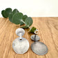 Silver earrings on a wooden surface with a small sprig of eucalyptus leaves