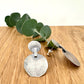 Silver earrings on a wooden surface with a small sprig of eucalyptus leaves