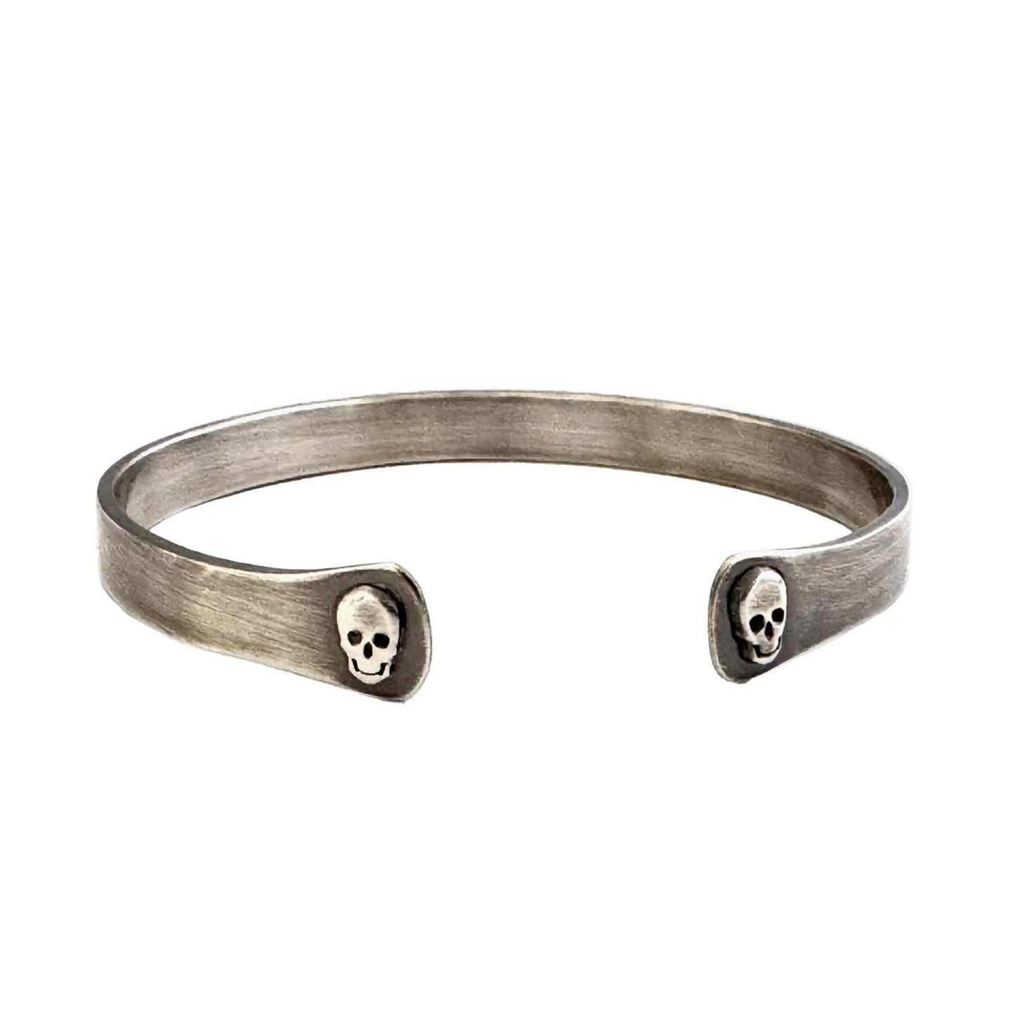 Oxidised sterling silver cuff bracelet with skull designs on a white background