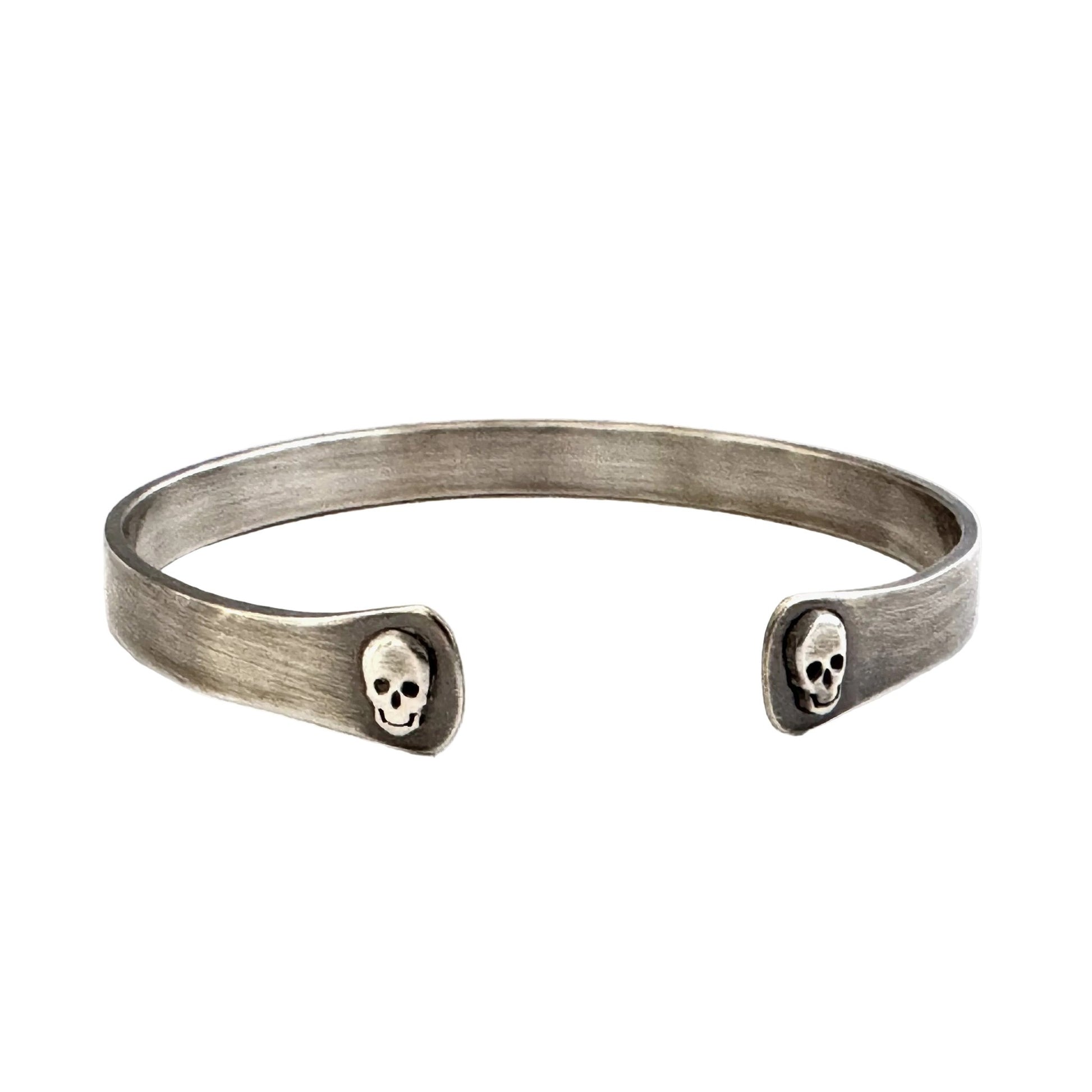 Oxidised sterling silver cuff bracelet with skull designs on a white background