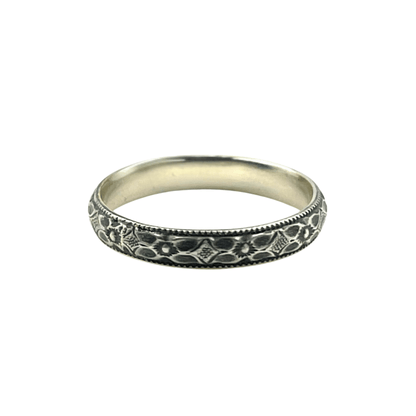 An oxidised sterling silver stacking ring with an engraved flower pattern against a bright white background | Rebecca Cordingley Jewellery