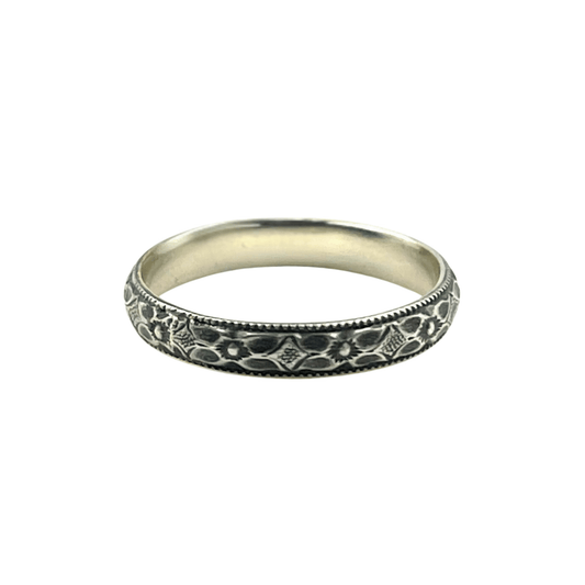 An oxidised sterling silver stacking ring with an engraved flower pattern against a bright white background | Rebecca Cordingley Jewellery