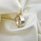 Flat sterling silver wedding ring with a brush finish against a cream satin background - Rebecca Cordingley Jewellery