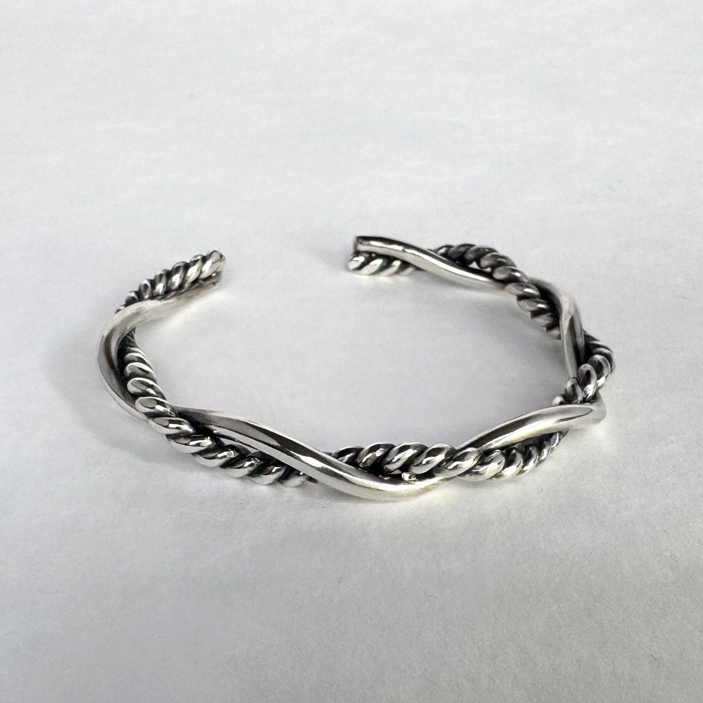 Oxidised sterling silver braided cuff bracelet on a light grey background