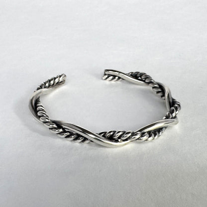 Oxidised sterling silver braided cuff bracelet on a light grey background