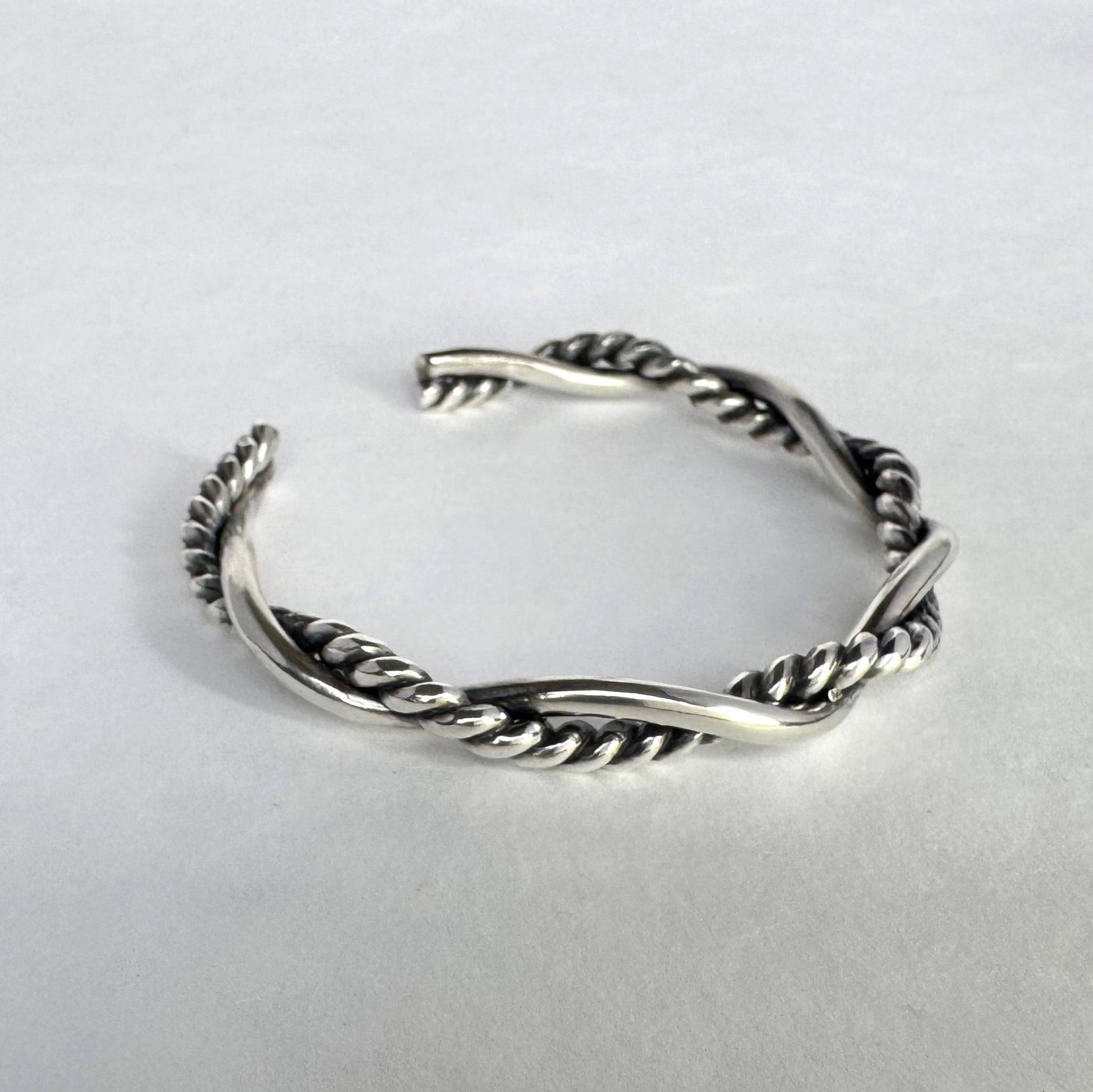Oxidised sterling silver braided cuff bracelet on a light grey background