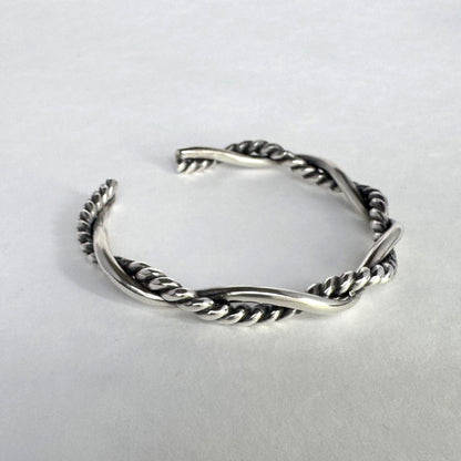 Oxidised sterling silver braided cuff bracelet on a light grey background