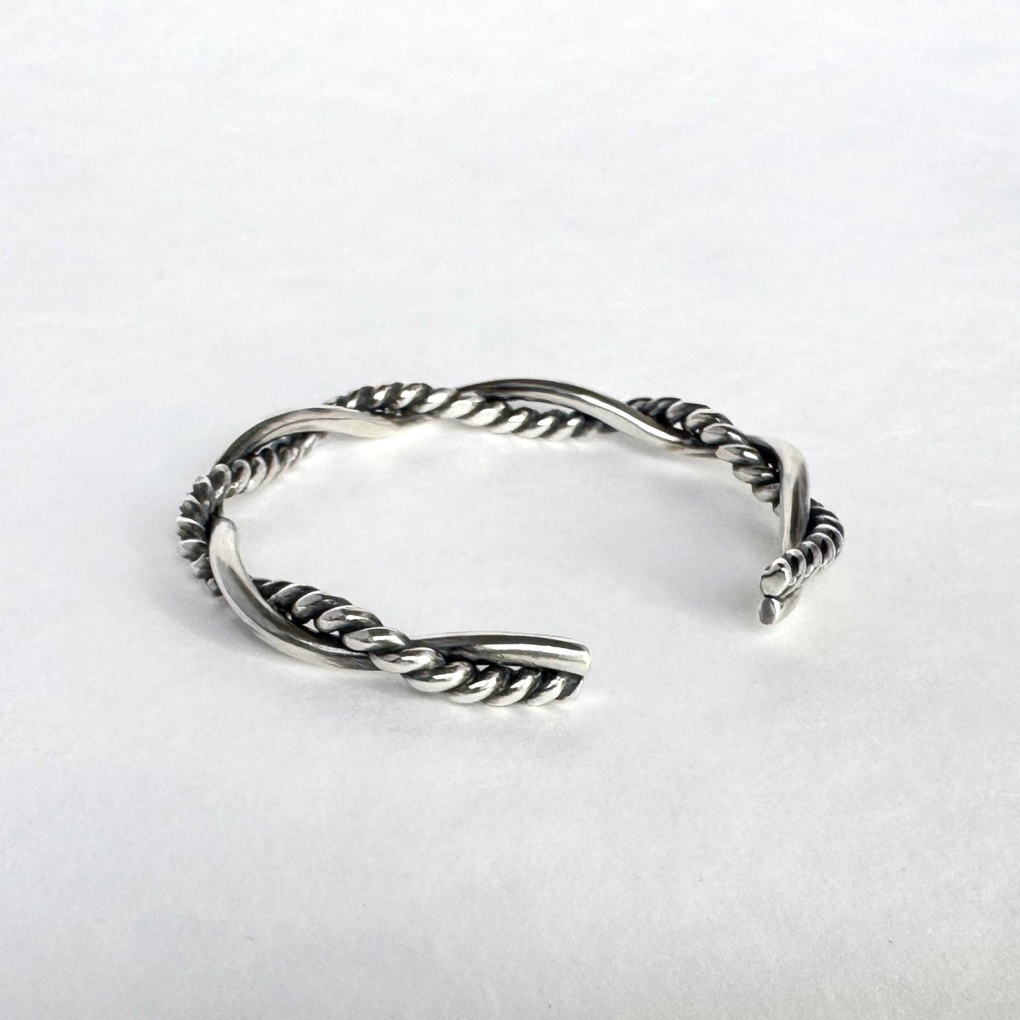 Oxidised sterling silver braided cuff bracelet on a light grey background