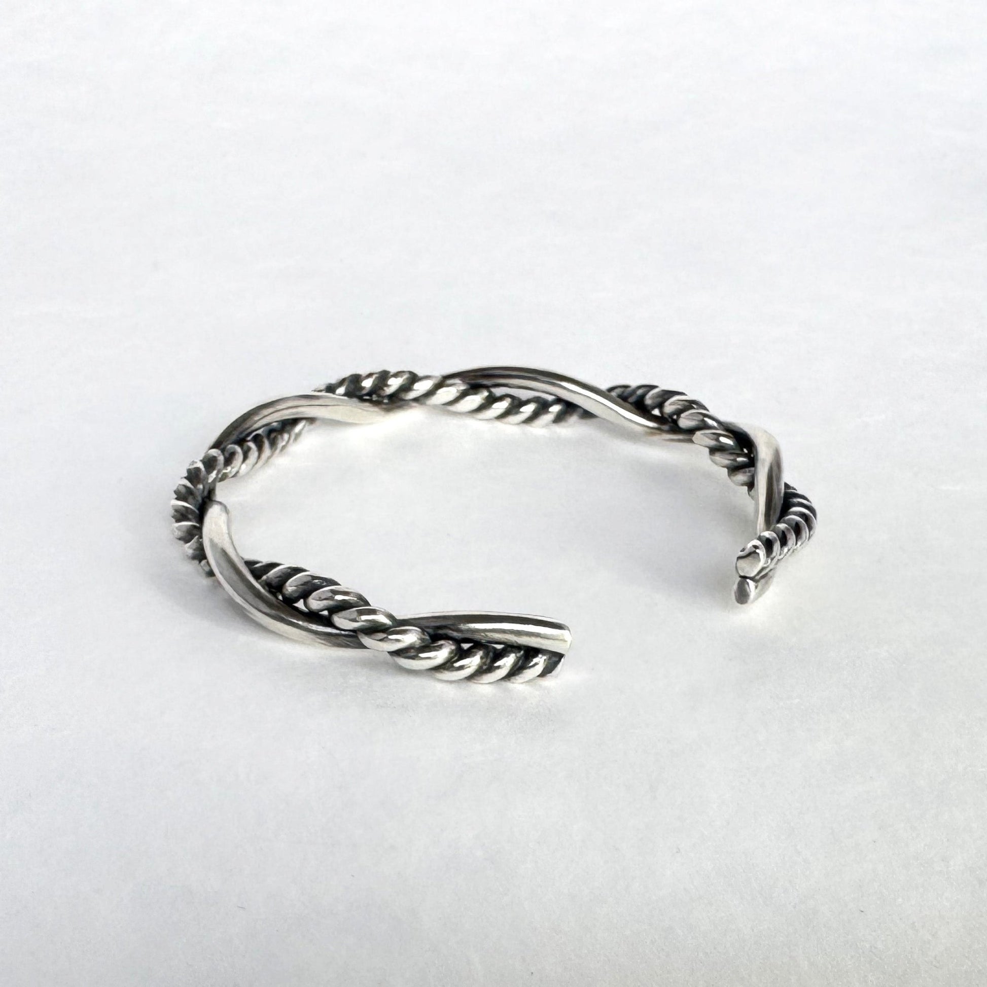 Oxidised sterling silver braided cuff bracelet on a light grey background
