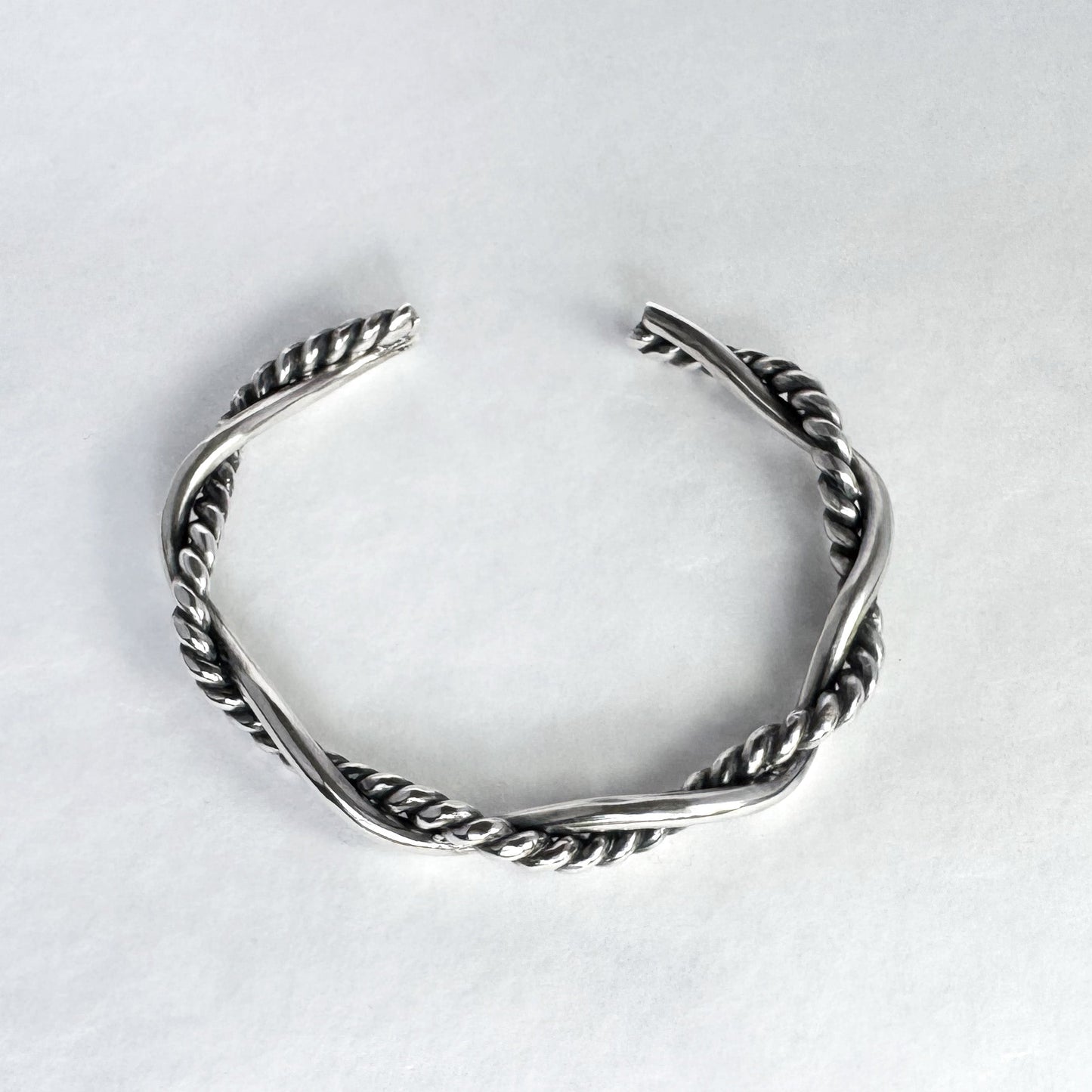 Oxidised sterling silver braided cuff bracelet on a light grey background