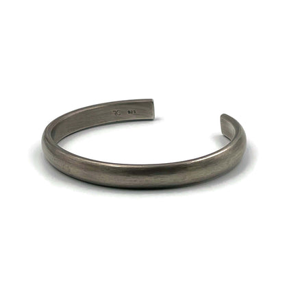 Heavy half-round sterling silver cuff bracelet with an oxidised finish on a white background.