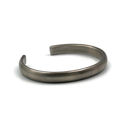 Heavy half-round sterling silver cuff bracelet with an oxidised finish on a white background.