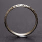 A sterling silver flower stacking ring standing up, side-on, on a dark grey background