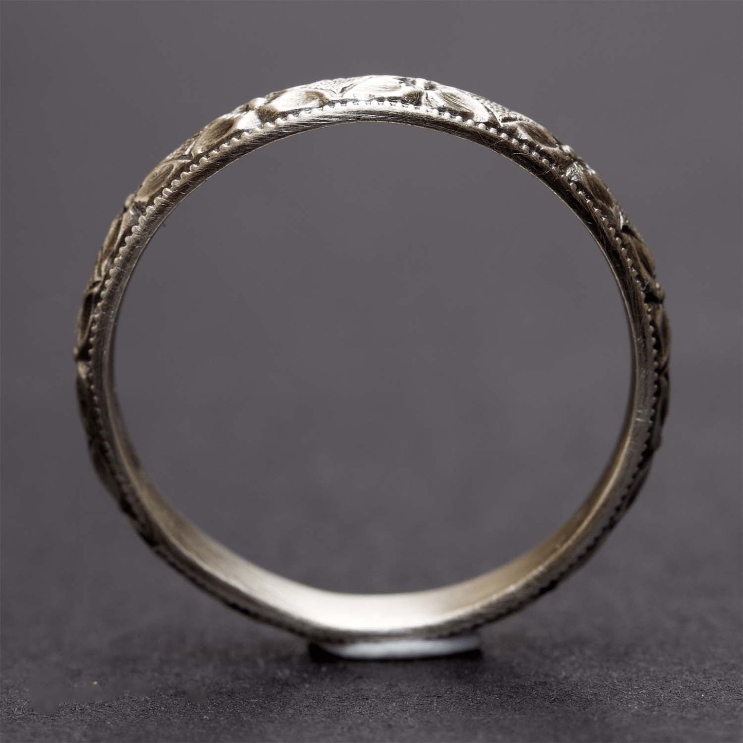 A sterling silver flower stacking ring on a dark grey background