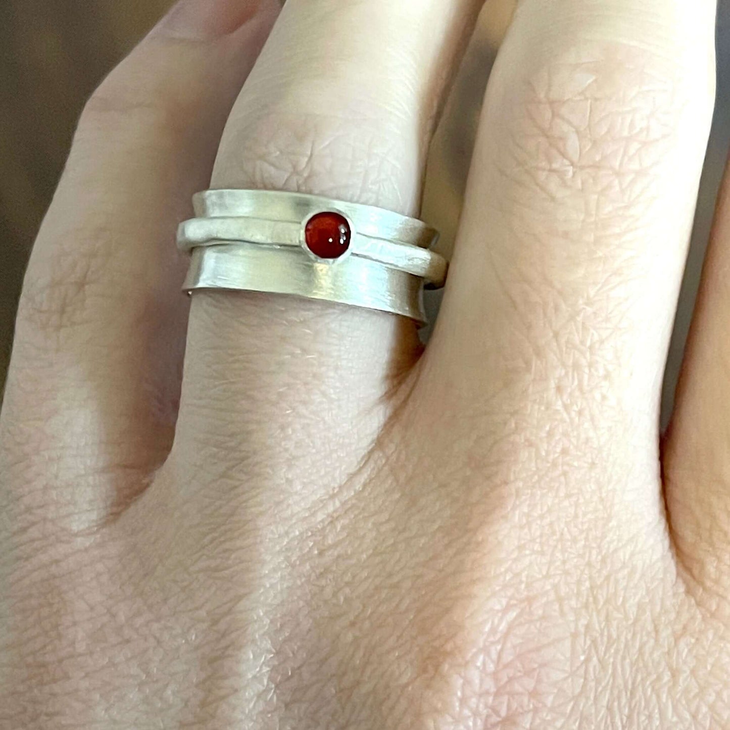Sterling silver spinner ring with carnelian cabochon on ring finger