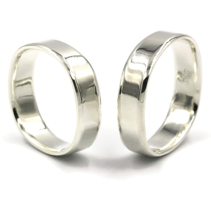 Pair of square sterling silver wedding ring with bevelled edges standing upright against white background, handmade in Australia